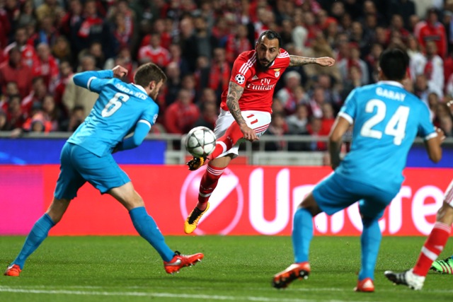 Na snímke uprostred hráč Lisabonu Kostas Mitroglou strieľa na bránu medzi hráčmi Zenitu, vľavo Nicolas Lombaerts, vpravo Ezequiel Garay v prvom zápase osemfinále Ligy majstrov vo futbale Benfica Lisabon - Zenit Petrohrad