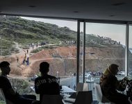 Ľudia sedia v reštaurácii s výhľadom na les, kde jevidieť migrantov mieriacich do španielskej exklávy Ceuta